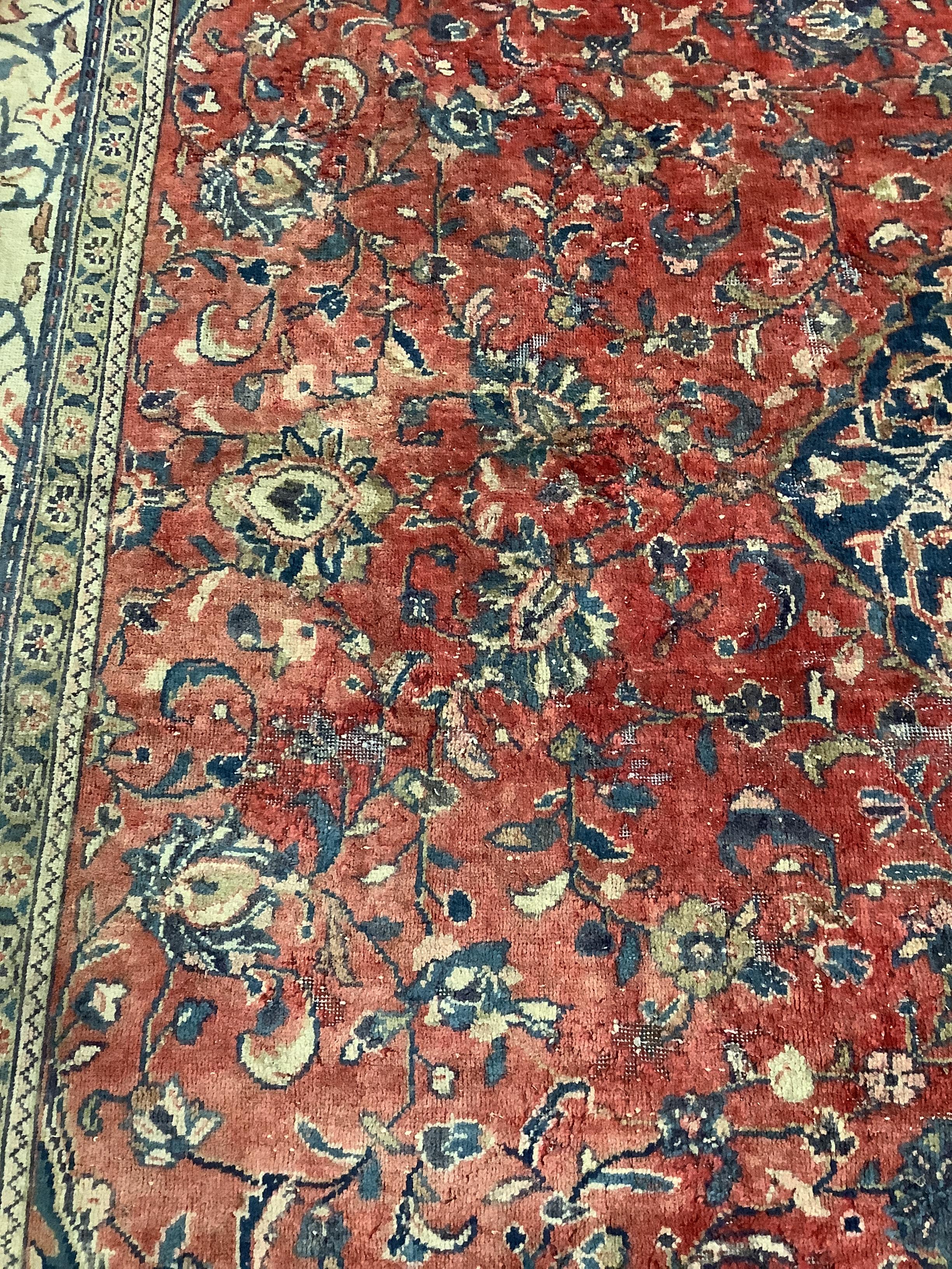 A Persian brick red ground carpet, 382 x 300cm (severely worn in patches)